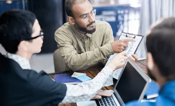 Colleagues reviewing a product plan together around a laptop